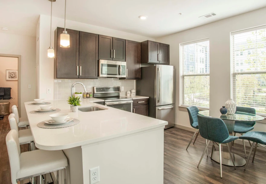 Stylish kitchen with dark cabinets, stainless appliances, and bright island bar seating