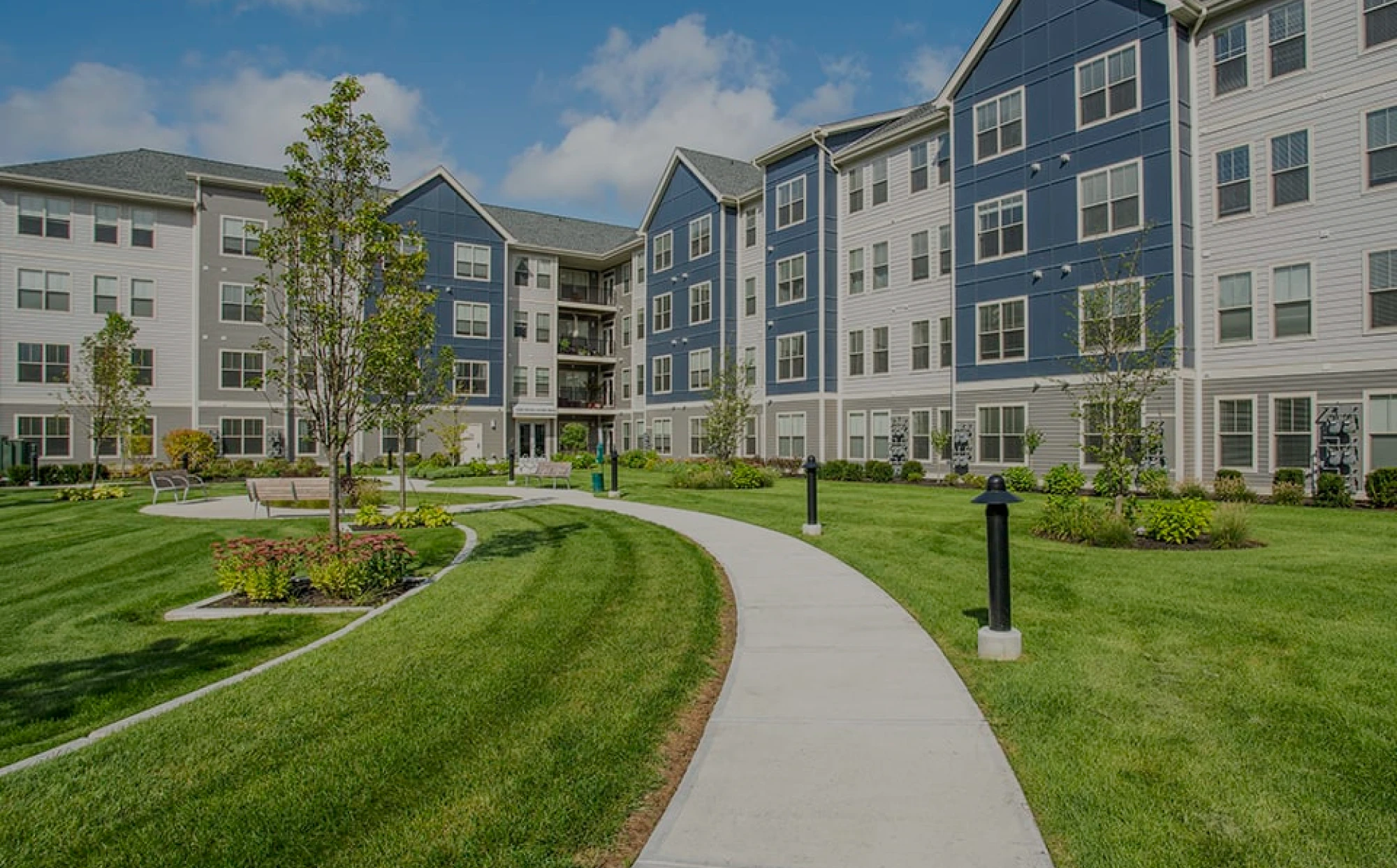 Manicured green space with walking path between multi-story apartment residences