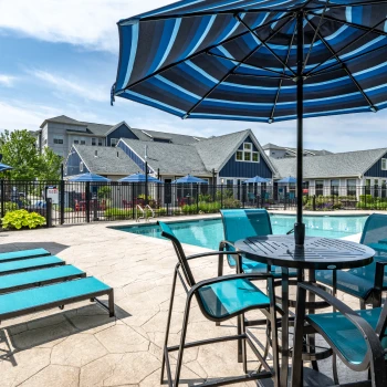 Resort-style swimming pool surrounded by turquoise lounge chairs and blue-striped patio umbrellas