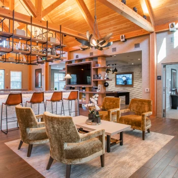 Cozy resident clubhouse with modern lounge seating and rustic wooden ceiling beams above