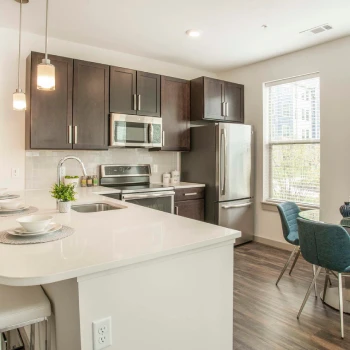 Contemporary apartment kitchen with stainless steel appliances and breakfast bar near large windows