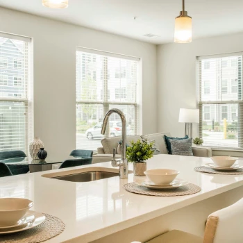 Kitchen island with seating for three, modern sink fixtures, and large windows letting in natural light