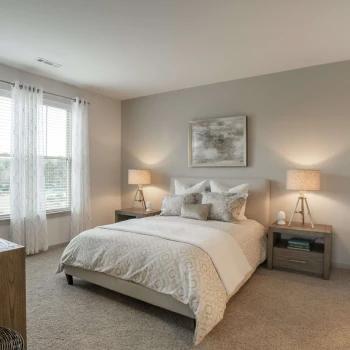 Serene bedroom space with queen bed, neutral decor, and natural light through two large windows