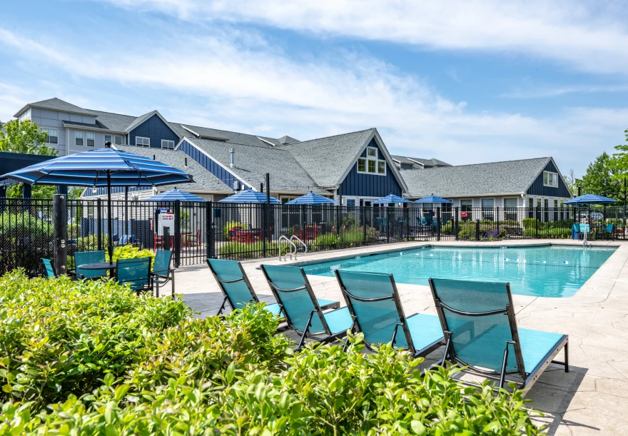 Sparkling residential swimming pool surrounded by lounge chairs and vibrant blue umbrellas